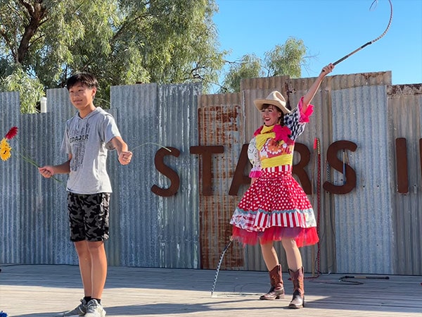 Amanda Lynn of The Crack Up Sisters cracks a whip on a flower held by audience member