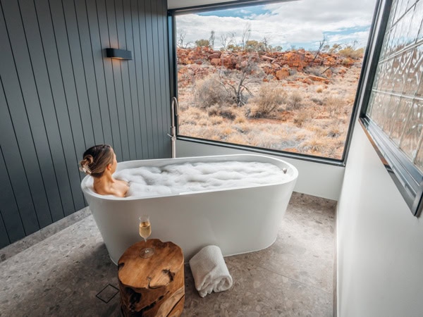 a woman relaxing in a tub inside her Deluxe Suite at Discovery Resorts - Kings Canyon