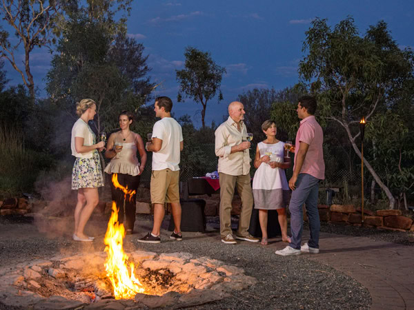 a group of people Dining Under A Desert Moon around a bonfire