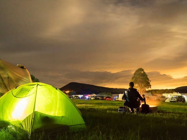 a man sitting by a bonfire outside his tent at Lake Moogerah Camping, Moogerah Peaks National Park, Scenic Rim
