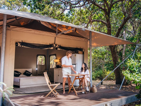 a couple relaxing outside their glamping tent at Minjerribah