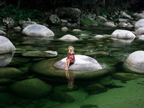 A woman sits on a rock in Mossman River