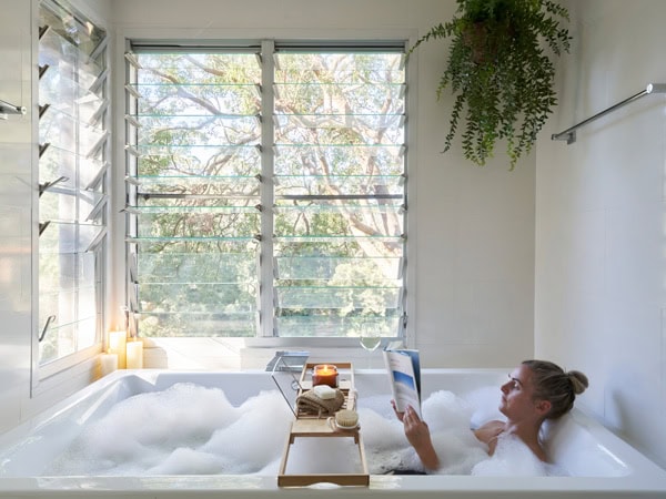 a woman dipping in the tub while reading a book