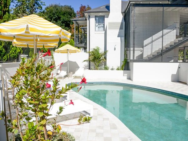 an outdoor pool with a yellow umbrella on the side at Wildes Boutique Hotel