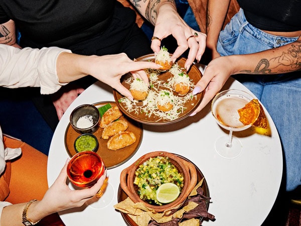 hands reaching for food on a plate at Backroom Bar