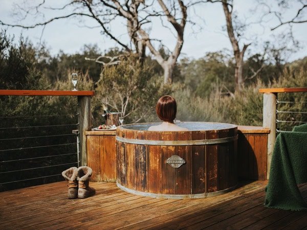 a woman dipping in a wooden outdoor tub at Cradle Mountain Lodge