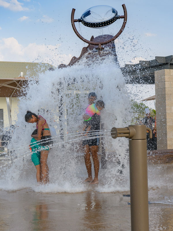 a family splashing around the fountain at the aquatic play area in Darwin Airport Resort