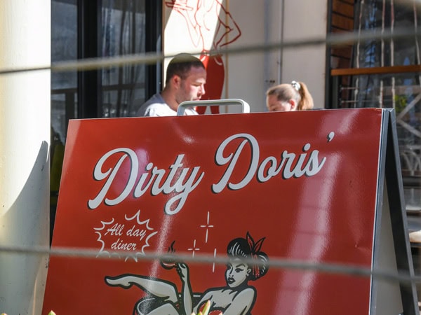 two people behind the Dirty Doris signage
