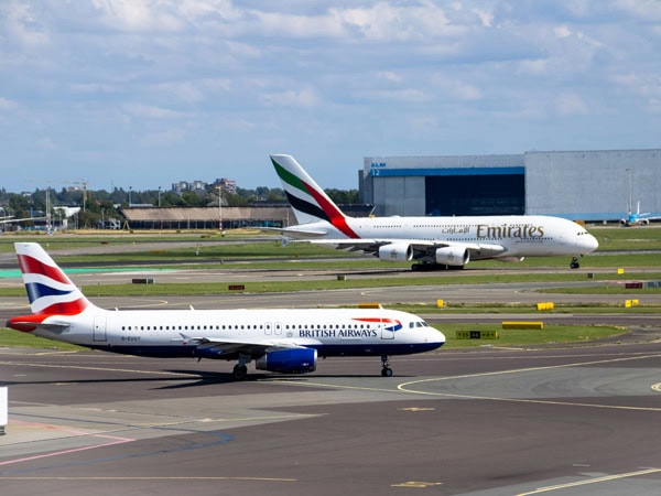 Emirates and British Airways planes sitting on the runway of an airport