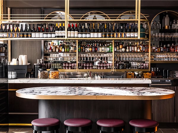 Beautiful backlit bar with a marble countertop and aubergine-hued stools at Georgie's Wine Bar in the CBD.