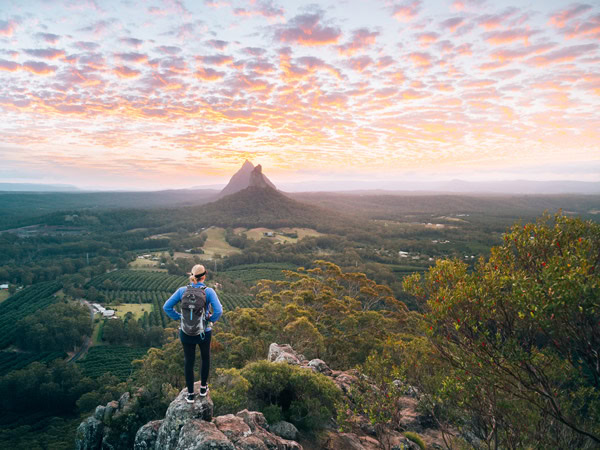 a hiker standing on top of Glasshouse Mountains