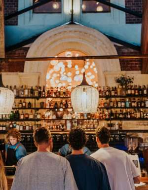 people lining up at the well-lit bar counter of Mr Chapple, Fremantle