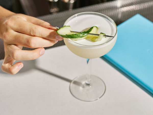 a hand touching a cocktail glass at Lina Rooftop Bar