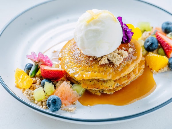 a plate of pancakes with sliced fruits at Little Black Pug Cafe