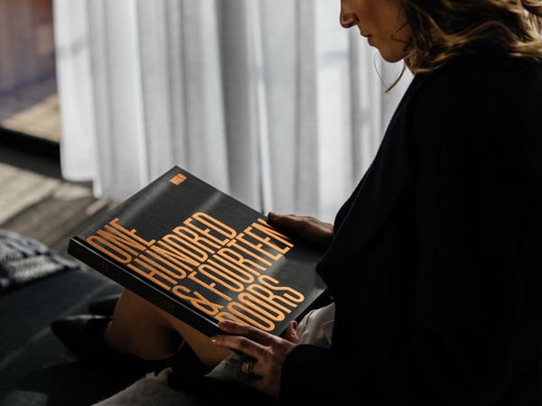 a woman holding a book of the 114 Doors Tour at MACq01, Hobart