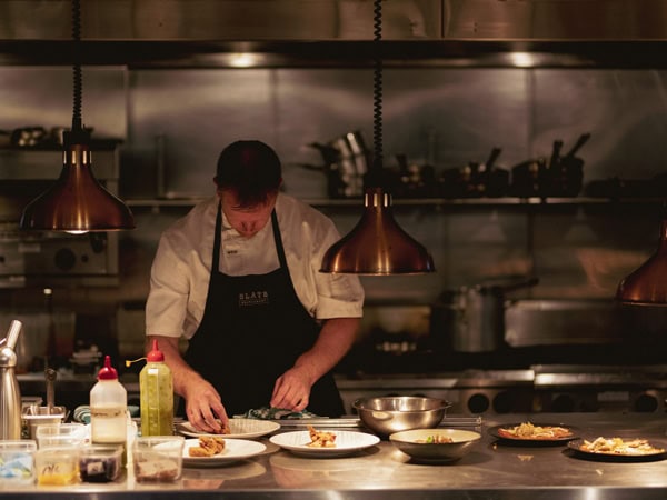 a chef doing meal preparations at Slate Restaurant at Pikes