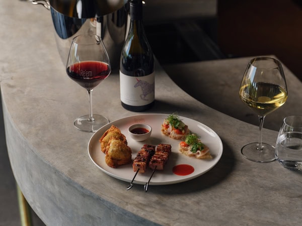 food on a plate beside a wine glass and bottle at Re’em, Yarra Valley, Vic
