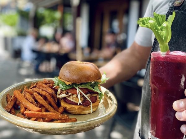 holding burger and fries on a plate with a drink at Sazón Espresso