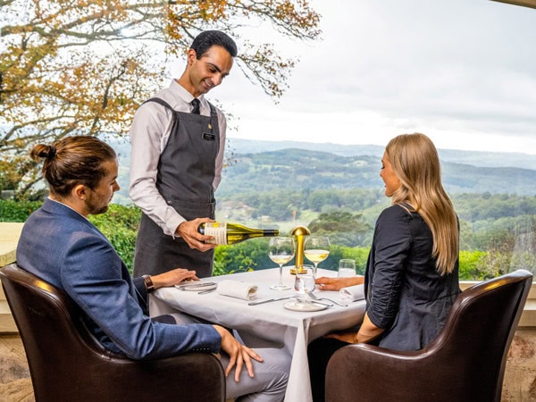 a waiter pouring wine into the glass in front of a couple dining at Sequoia 