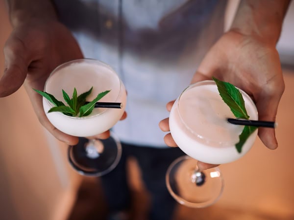 a close-up of a hand holding two cocktail glasses at Shirley’s Fremantle