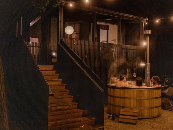 friends soaking in the outdoor woodfired hot tub at Sisters, Tas