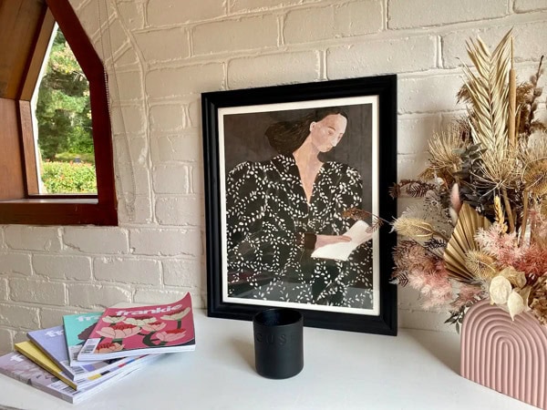 a painting of a woman beside flowers and books at The Coach House, Aldgate