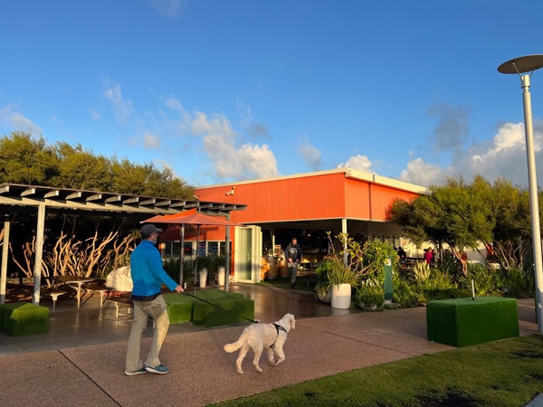 a man walking with his dog to The Orange Box, North Fremantle