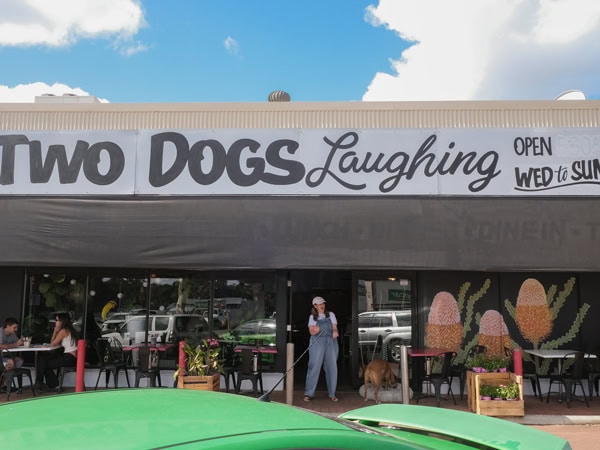 a woman with her dog at standing at the entrance door of Two Dogs Laughing cafe