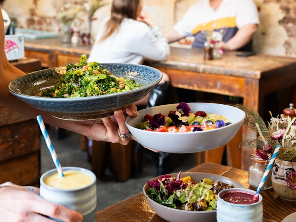 a person serving vegan dishes at Monk Bodhi Dharma cafe