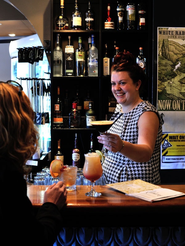 a bartender serving drinks to her customers at Alchemy Bar & Restaurant