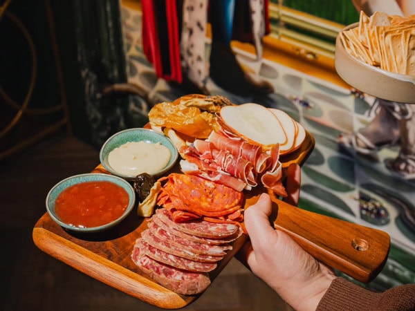 a hand holding a charcuterie board at Bar Urbane