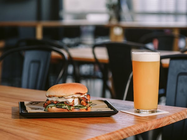 a glass of beer alongside a burger on the table at Brewlab, Hobart