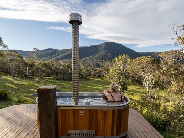 a woman soaking in an outdoor woodfired hot tub at Crafters Cabins