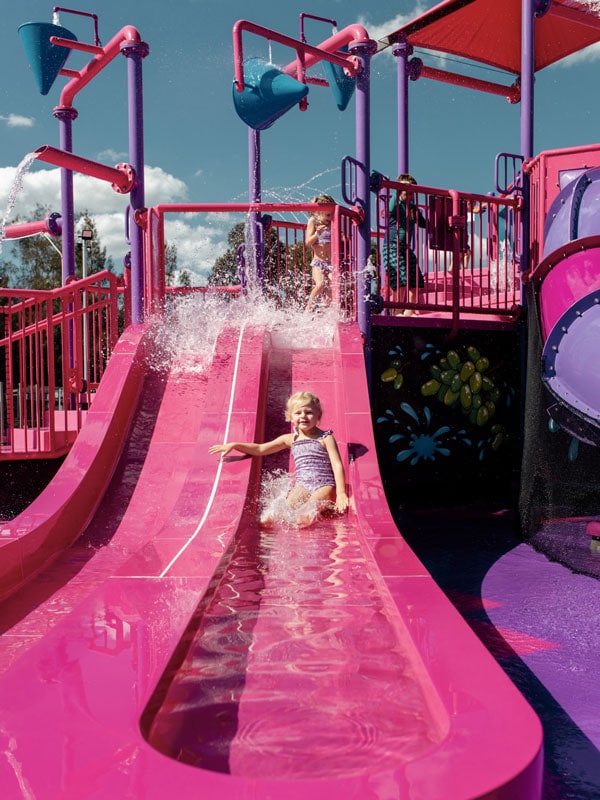 a kid sliding down a pink slide at the water park of Rydges Hunter Valley