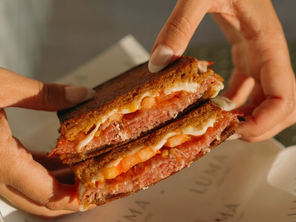 a hand holding a toastie at LUMA Coffee Club, Adelaide