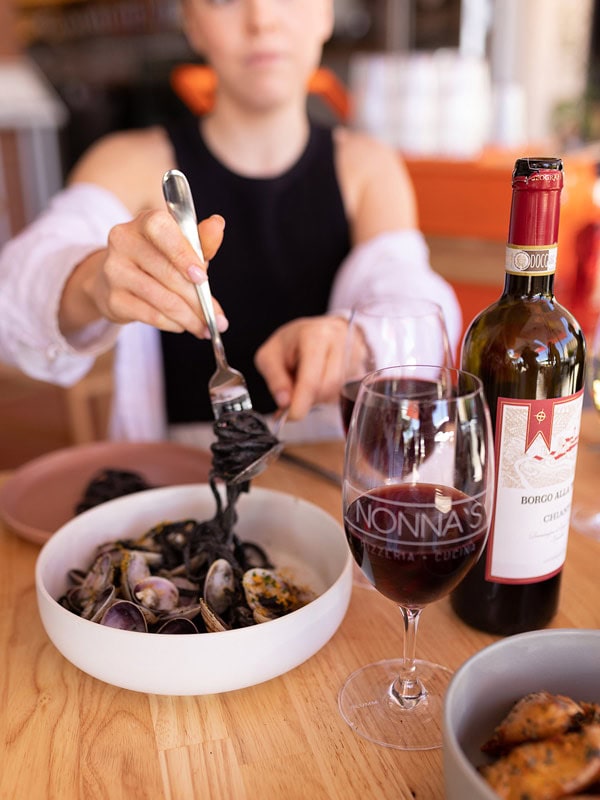 a woman dining pasta with wine at Nonna’s Pizzeria & Cucina