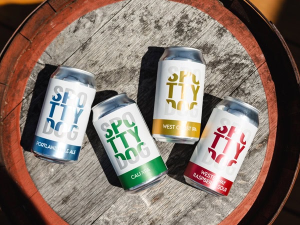 cans of beer on top of a barrel at Spotty Dog Brewers