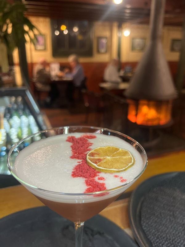 a close-up shot of a cocktail glass by the log fire at hree Steps on George pub in Launceston