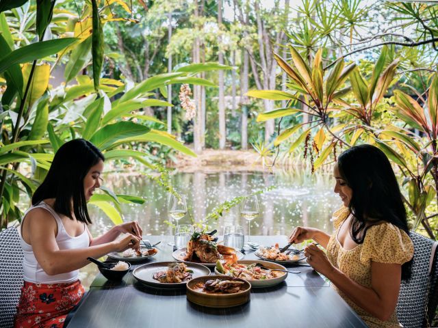 two women dining in a tropical garden by the river at Spirit House, Sunshine Coast