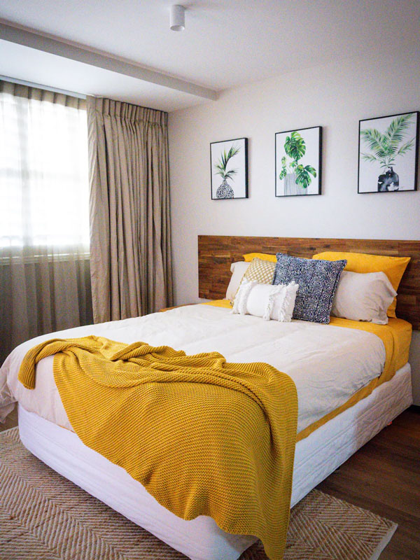 a bed with white sheets and yellow blanket at the cosy city edge studio Airbnb in Perth