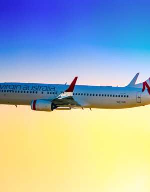 a Boeing 737-800 in Virgin Australia colour scheme taking off from Sydney (Kingsford Smith) Airport on a late afternoon. The plane is bound for Gold coast Queensland