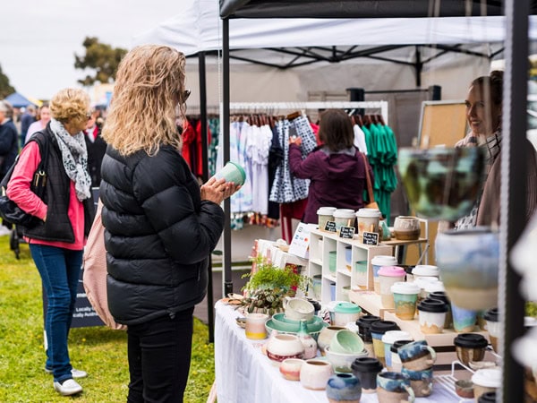 a woman holding a ceramic at a stall in Port Fairy Market
