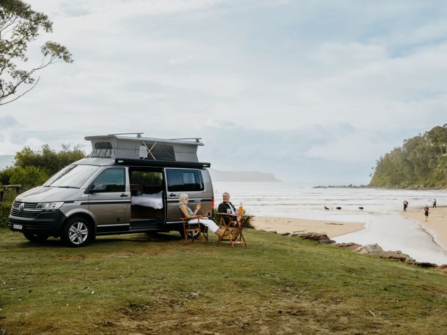 a couple sitting in front of a campervan at NRMA Ocean Beach Resort, Umina Beach