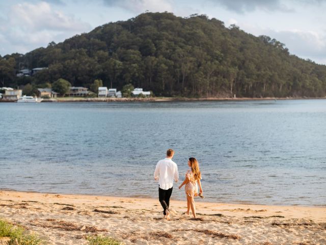 a couple walking along Ettalong Beach at sunset