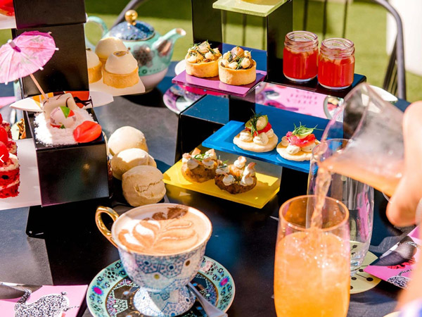 pouring a drink into a glass beside sugary treats, QT Gold Coast high tea