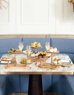 High tea served on a marble table around blue banquette seating at Hearth Restaurant at The Ritz Carlton, Perth
