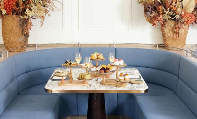 High tea served on a marble table around blue banquette seating at Hearth Restaurant at The Ritz Carlton, Perth
