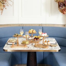 High tea served on a marble table around blue banquette seating at Hearth Restaurant at The Ritz Carlton, Perth