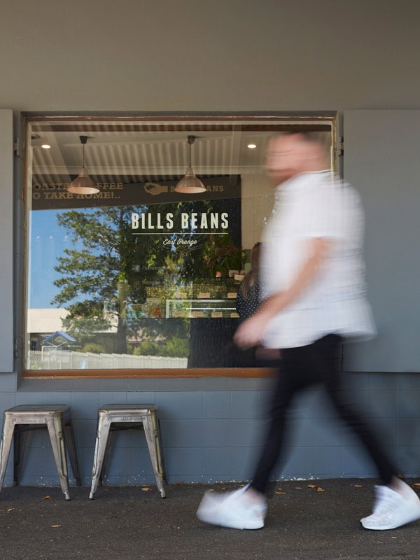a blurry image of a man walking in front of Bills Beans East Orange cafe