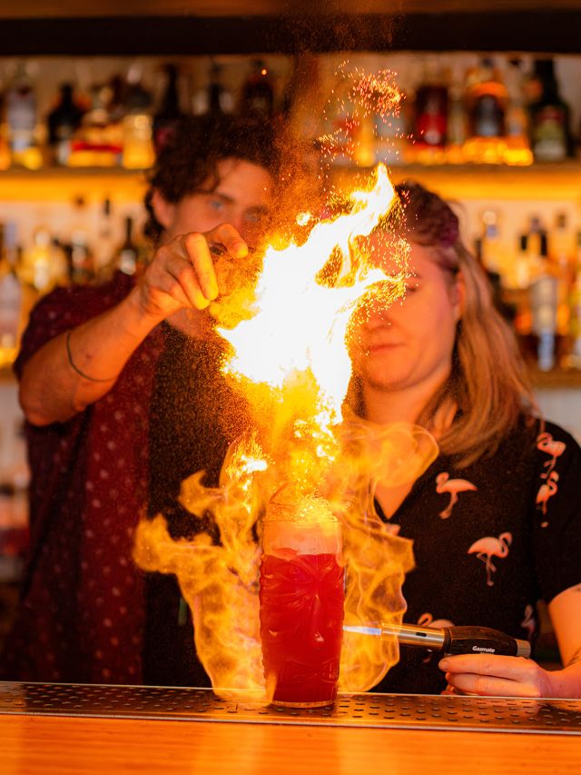 a fiery cocktail being prepared at Flamingos Tiki Bar